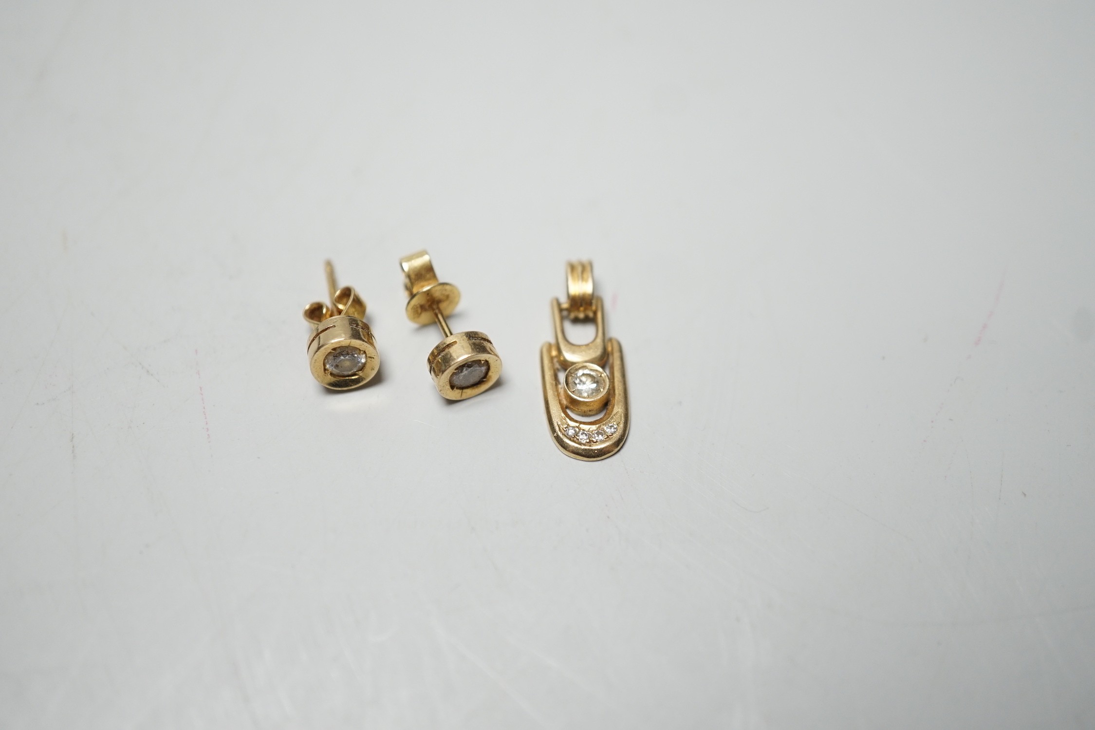 A modern pair of 585 yellow metal and solitaire diamond set ear studs, 6mm and a matching pendant, gross weight 3.9 grams.